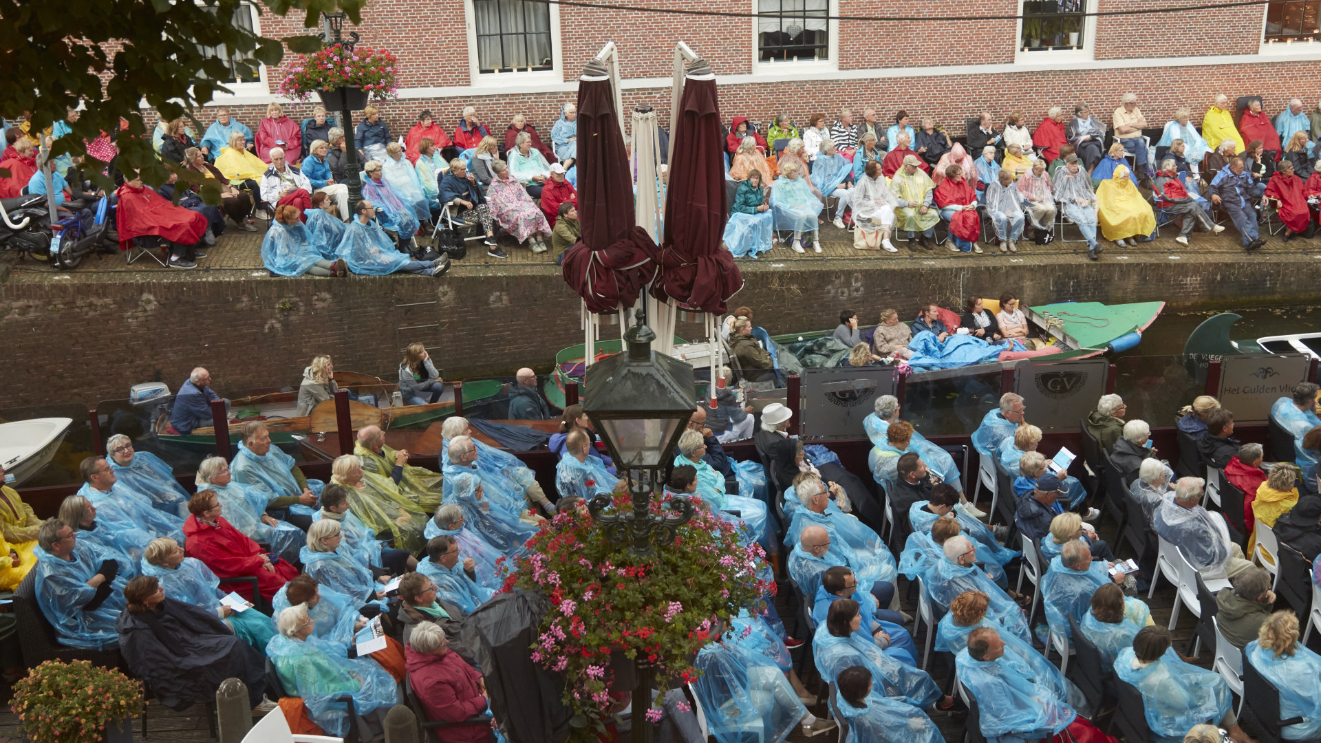 Publiek voorzien van poncho's tegen de regendruppels begin avond - Foto: Alef Starreveld